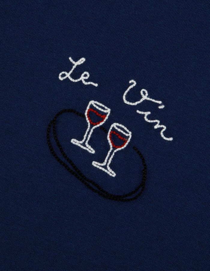 Patch du T-shirt bleu marine à manches courtes pour homme en coton biologique, modèle Popincourt de la marque Maison Labiche. Présente une coupe droite avec col rond côtelé et une petite broderie fine 'Wine' sur le côté gauche de la poitrine.