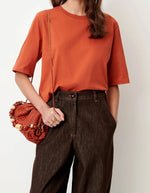 Vue de face du T-shirt col rond à manches courtes pour femme en coton bio orange brûlé avec fentes sur les côtés, modèle T-Shirt Serge couleur Red Muse de la marque Sessùn.