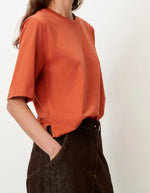 Profil du T-shirt col rond à manches courtes pour femme en coton bio orange brûlé avec fentes sur les côtés, modèle T-Shirt Serge couleur Red Muse de la marque Sessùn.