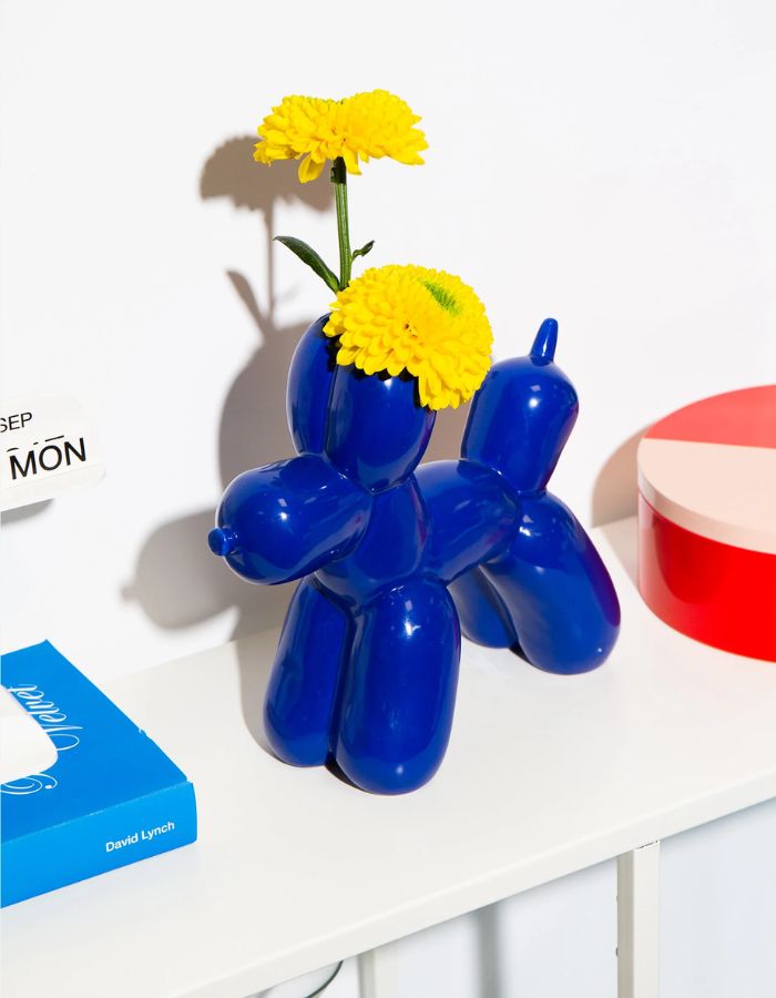 Fleurs jaunes dans le Vase en céramique bleu électrique Bobby par la marque DOIY. Design sculptural et géométrique avec des découpes graphiques modernes, mesurant 25 cm de longueur.