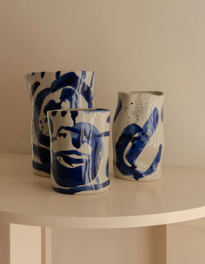 Trio des vases en grès artisanal Sophia par Marie Michielssen, de couleur blanche avec des motifs calligraphiques peints à la main en bleu profond. Silhouette organique asymétrique et design minimaliste de 19 cm de hauteur.