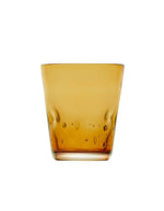 Vue de face du verre à eau artisanal Memento Dune couleur ambre, en pâte de verre soufflée à la bouche avec des ondulations naturelles et une forme pincée ergonomique.