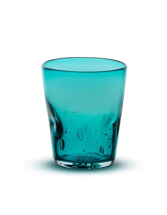 Verre à eau artisanal Memento Dune couleur bleu pétrole, en verre soufflé à la bouche avec forme ondulée ergonomique et reflets bleu-vert profonds.
