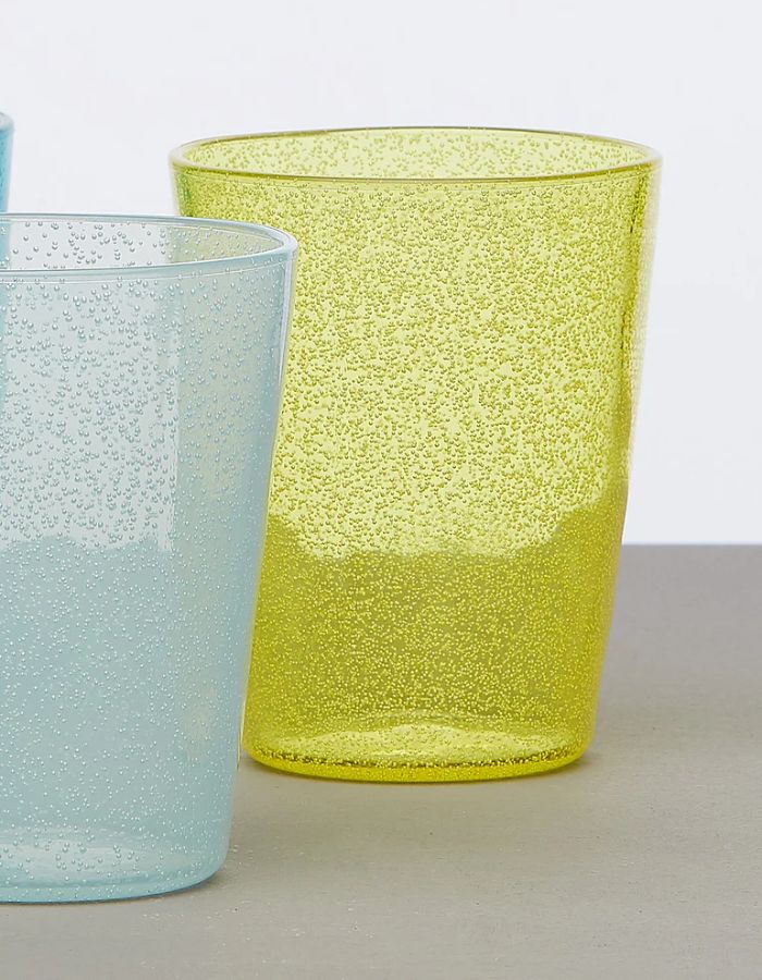 Verre en plexi jaune Memento Synth avec bulles d'air délicates, à côté d'un verre bleu similaire.