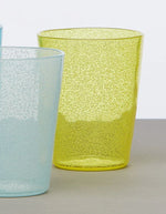 Verre en plexi jaune Memento Synth avec bulles d'air délicates, à côté d'un verre bleu similaire.