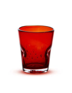 Verre à eau artisanal Memento Dune couleur rouge rubis, en verre soufflé à la bouche avec forme ergonomique ondulée et reflets brillants.