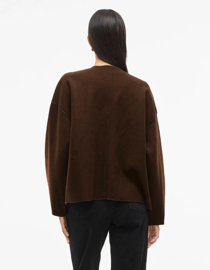 Silhouette de dos avec la Veste légère et ample pour femme de couleur marron foncé Coffee Bean, modèle Juice de la marque Vila. Présente un col en V, des manches longues à emmanchures tombantes et une fermeture discrète par boutons-pression.