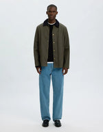 Silhouette avec la Veste courte pour homme en coton huilé kaki déperlante avec col rabattu et fermeture à boutons-pression, modèle Veste Kaki Coton Huilé Walter de la marque Selected Homme avec tissu Halley Stevensons.