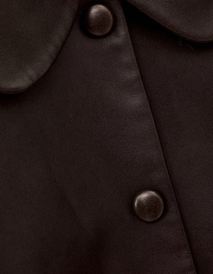 Boutonnière de la Veste courte pour femme en cuir d'agneau marron avec col claudine, manches mi-longues et boutons-pression recouverts, modèle Milos de la marque ba&sh.