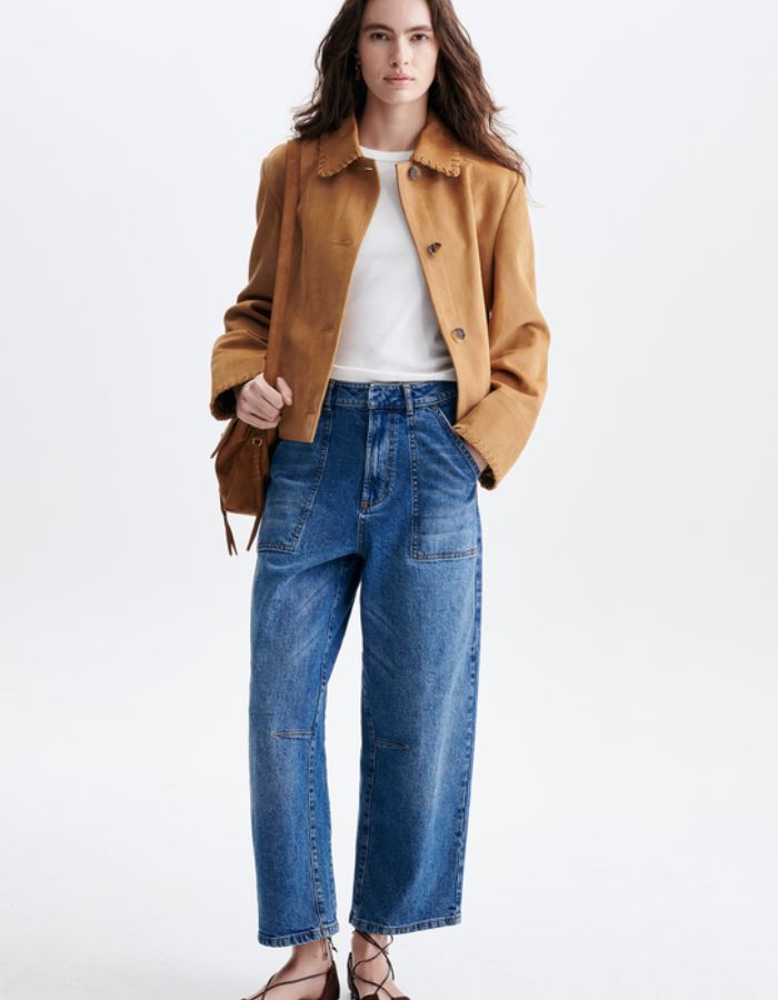 Silhouette avec la Veste courte pour femme en daim chèvre camel, modèle Hector de la marque VANESSA BRUNO. Présente un col claudine, une finition lacet en cuir noué à la main et des boutons en corne fantaisie.