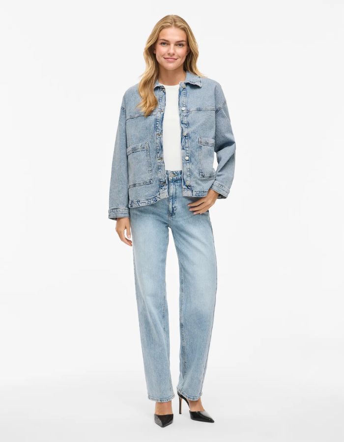Femme portant une veste en jean denim bleu clair Jaf avec col chemise, poches plaquées et fermeture boutonnée.