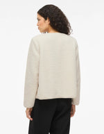 Silhouette de dos avec la Veste courte pour femme effet moumoute fausse fourrure de couleur beige écru, modèle Ada Teddy Jacket de la marque VILA. Présente un col chemise rabattu, des manches longues et une fermeture boutonnée sur le devant.