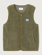 Veste sans manches pour homme de couleur vert kaki Varan Chiné, modèle Hoktown de la marque American Vintage. Confectionnée dans une matière épaisse effet mouton retourné shearling, elle présente un col montant bas, une fermeture à boutons-pression, deux poches zippées et un patch logo sur la poitrine.
