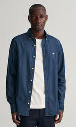 Homme portant une chemise slim fit indigo en chambray de coton avec col boutonné et écusson Gant.