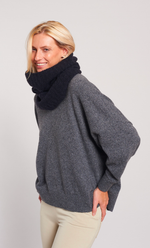 Femme souriante portant un snood noir en alpaga doux et un pull gris.